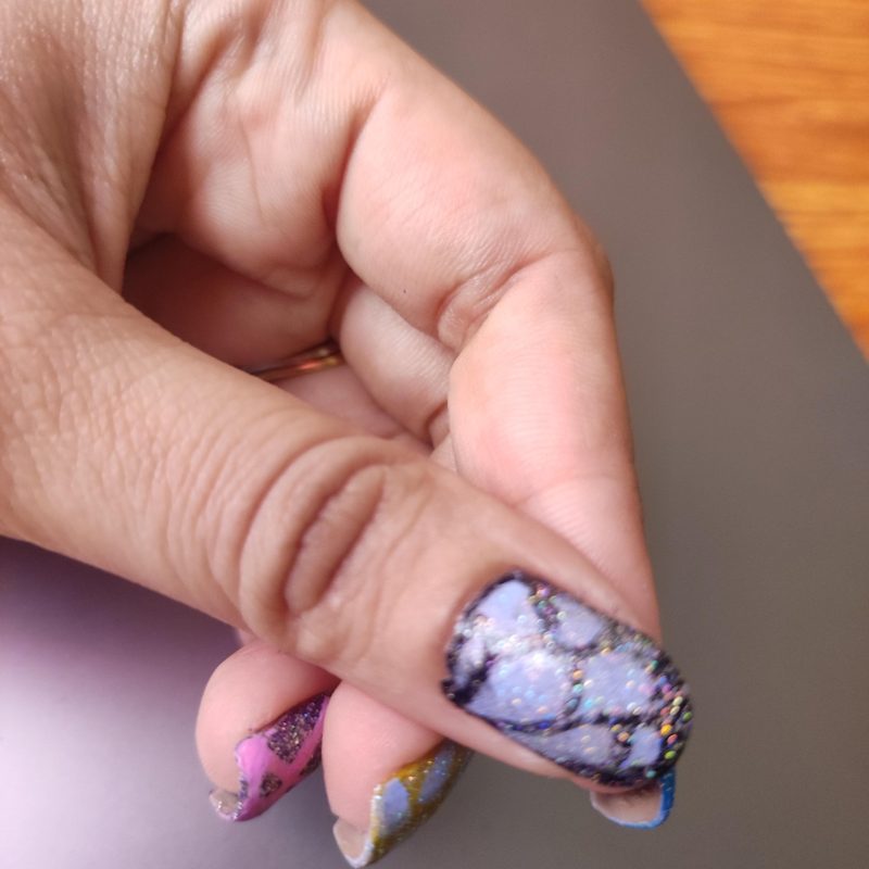 Hand applying detailed design on nails using a gel nail art pen