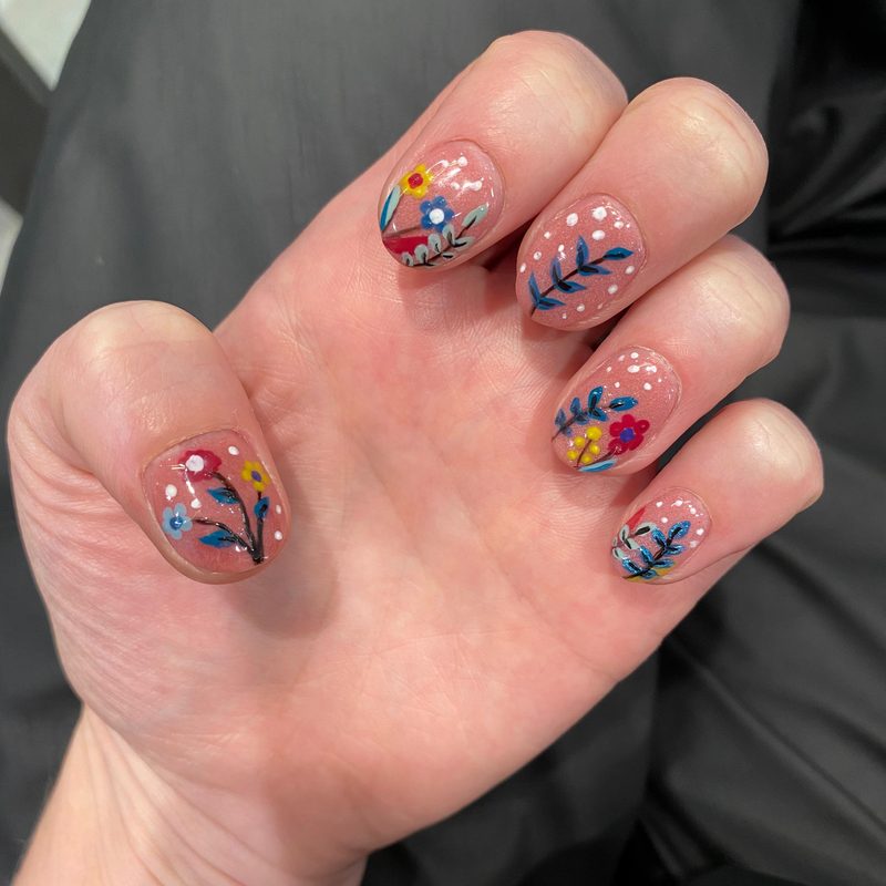 nail artist using a nail art brush to create detailed black nail designs