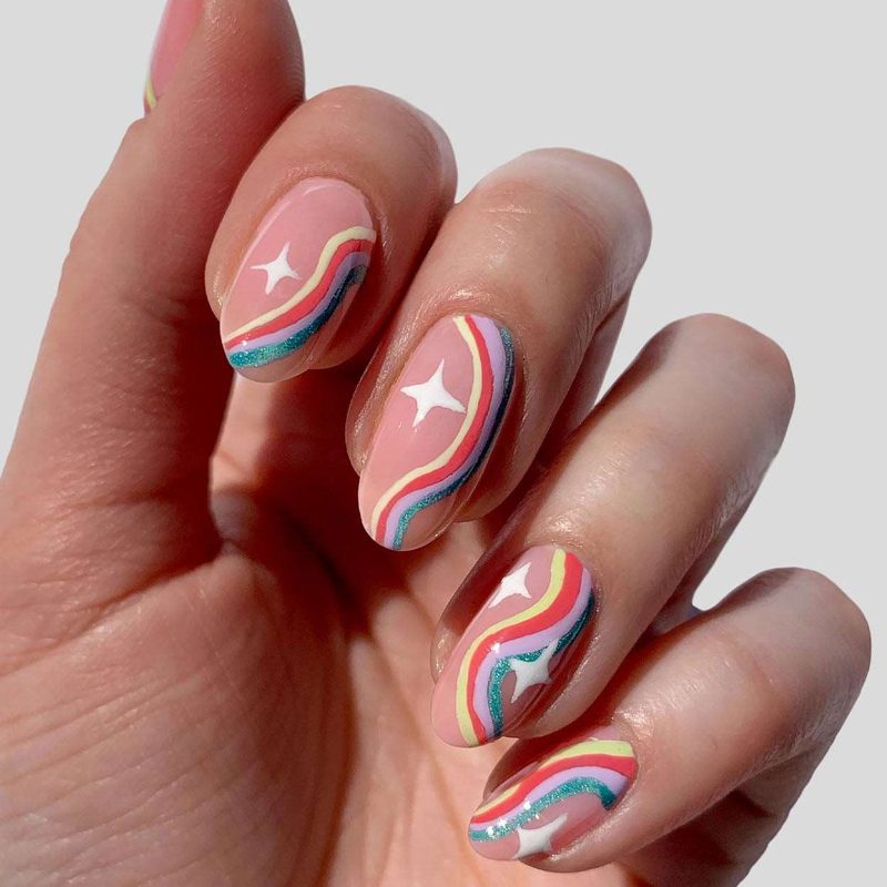 Close-up of a fine nail art brush applying detailed nail art strokes