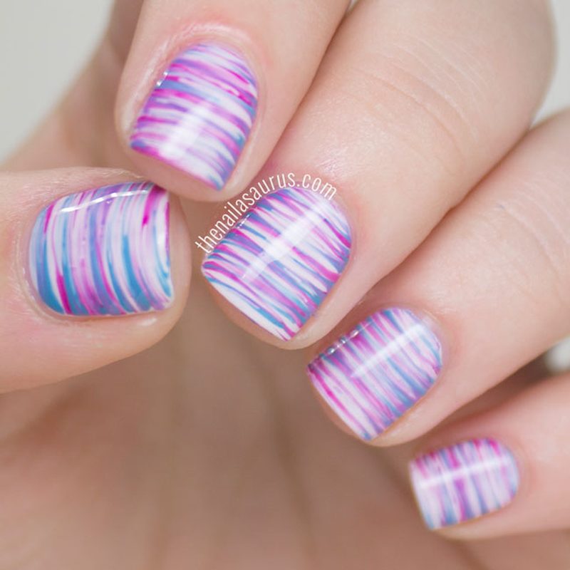 Close-up of nails featuring ombre and feathered fan brush nail art designs