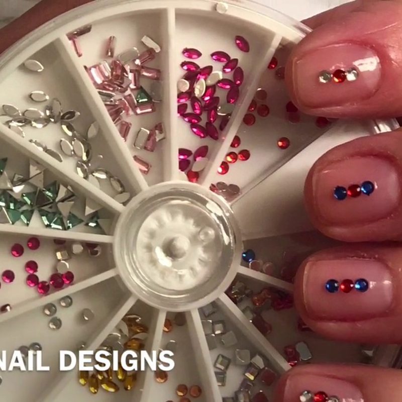 hands applying rhinestones for nail art with tweezers