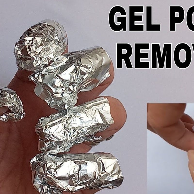 Hands soaking gel nails with foil art during removal process