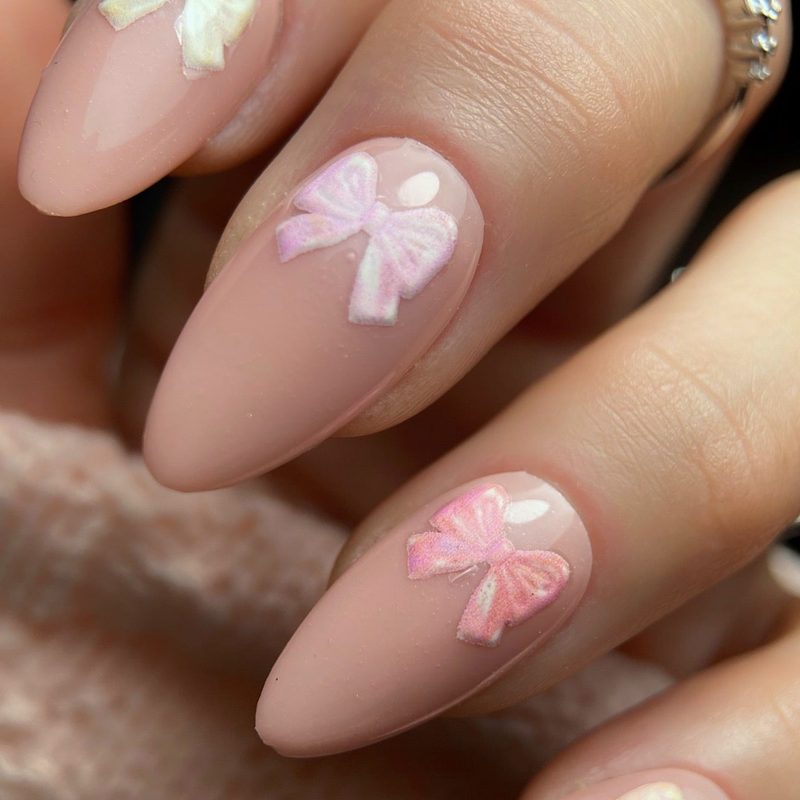 professional nail technician creating pink ribbon nail art at a salon