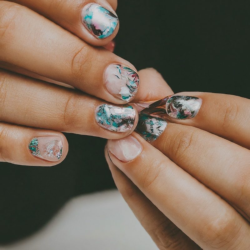 Various foil nail art on gel nails featuring metallic and holographic designs