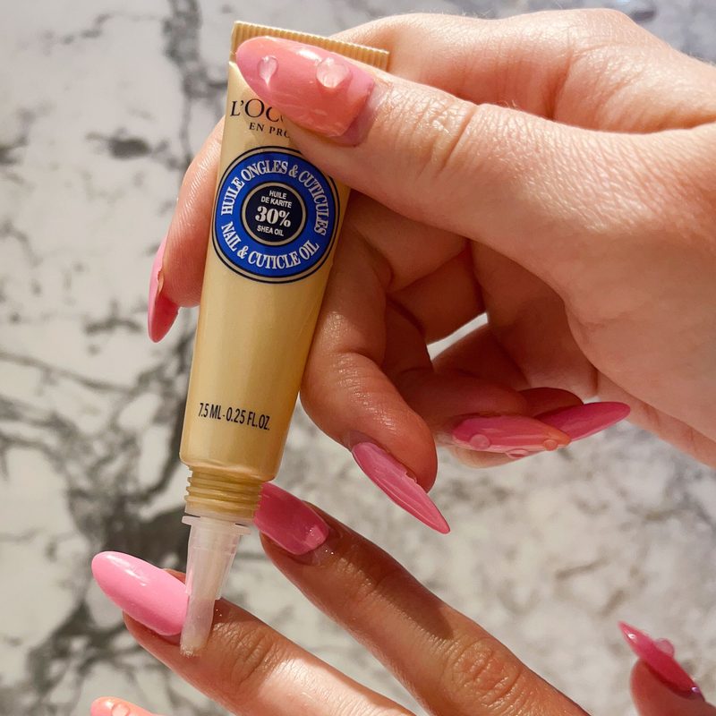 Woman applying cuticle oil to maintain top coat nail art