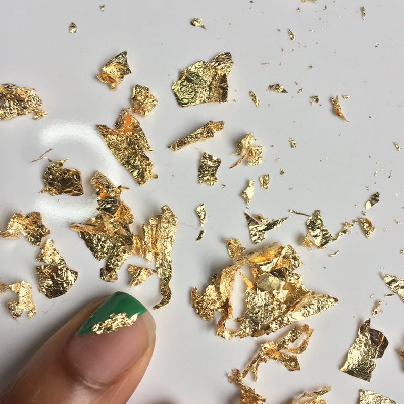 close-up of hand applying nail art foil flakes with tweezers