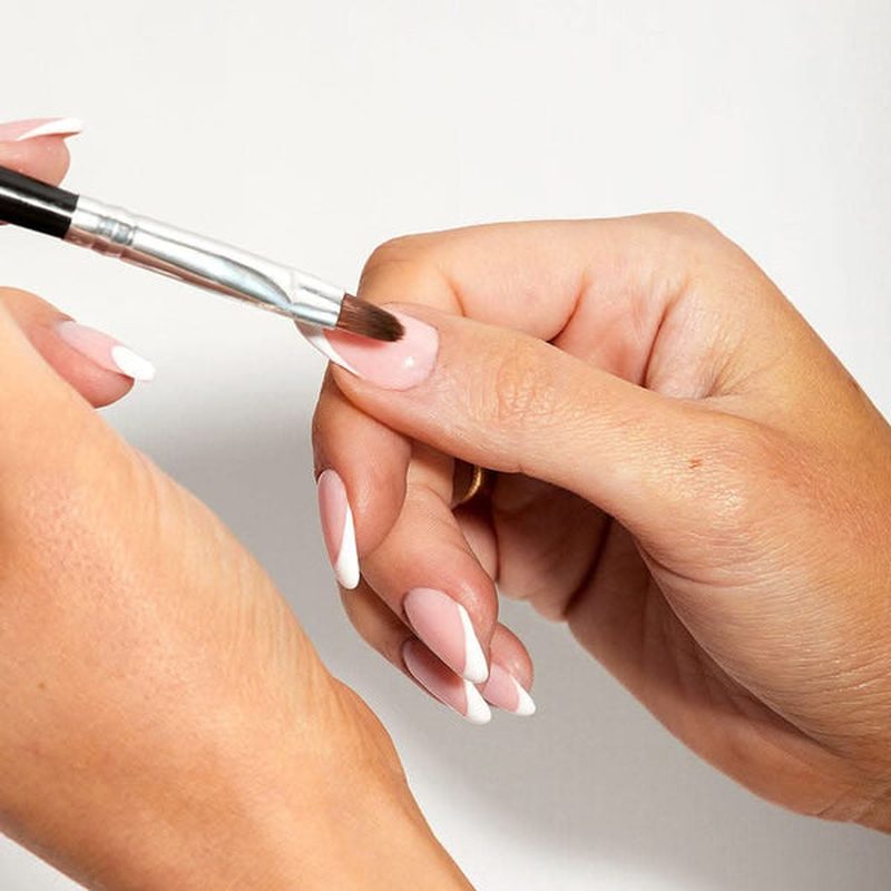 close-up of hand applying nail art paint gel with precision brush