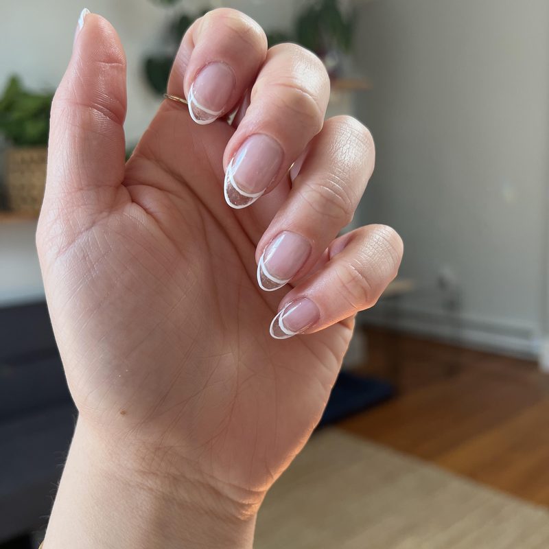 close-up of hand painting detailed nail art with thin brush