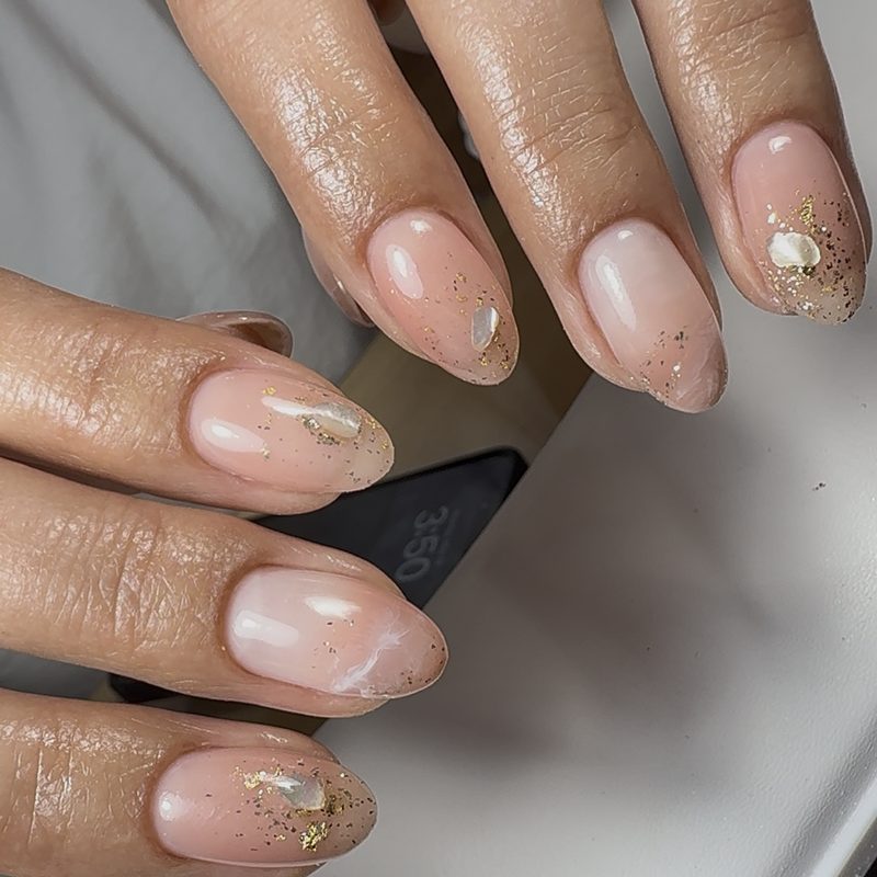 Close-up of nails being sealed with a gel top coat to protect nail foil designs
