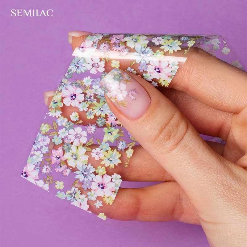 Hands applying nail art transfer foil using adhesive on nails