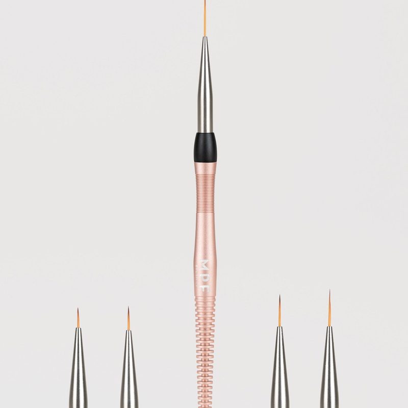 nail salon technician applying precise nail art with liner brush