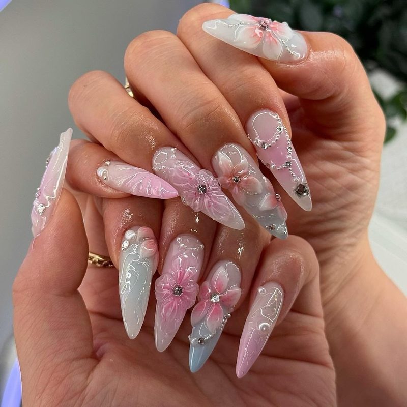 Nails featuring creative nail art with charms combining floral and geometric designs