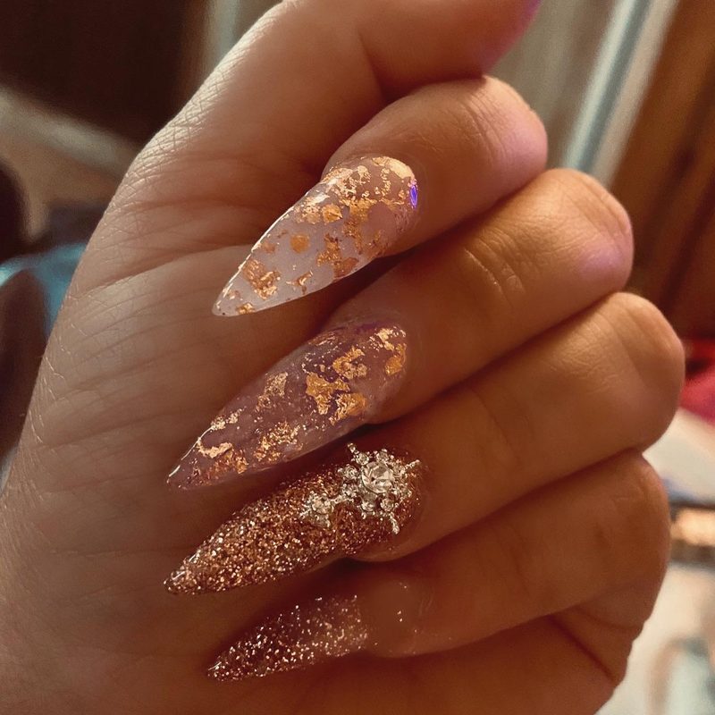 woman applying top coat to nails with foil flakes design